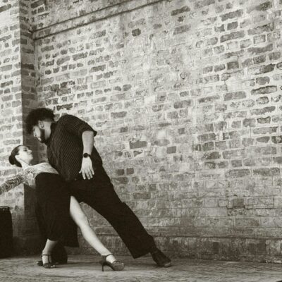 A man and a woman leaning against a brick wall